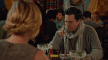 a man sitting at a table talking to a woman who says it 's hot hot hot