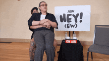 two people hugging in front of a sign that says hey ew