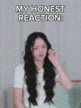 a woman with long hair is sitting in a chair and making a face with her hands .