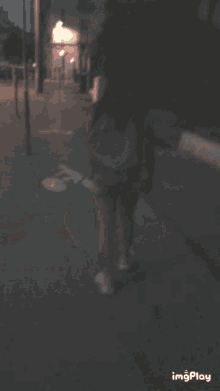 a blurry photo of a woman standing on a sidewalk with the word imgplay on the bottom