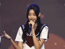 a girl in a school uniform is holding a microphone