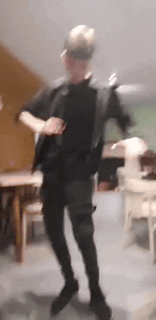 a blurry picture of a man dancing in a room with tables and chairs .