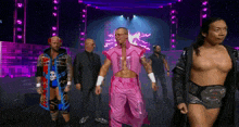 a group of men are walking on a stage and one of them is wearing a pink outfit
