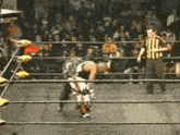 a referee stands in a wrestling ring watching a wrestler