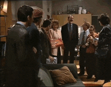 a group of people are standing around a couch talking to each other