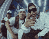 a man wearing sunglasses and a bandana is pointing