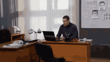 a man sits at a desk in front of a laptop
