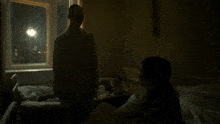 a man is standing in a dark room next to a bed