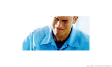 a man in a blue shirt is rubbing his eyes while listening to music