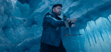 a man in a black jacket is holding a hammer in a cave .