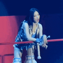 a woman is standing in a wrestling ring holding a microphone and giving a middle finger .