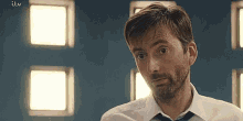 a man with a beard is wearing a white shirt and tie and making a funny face .