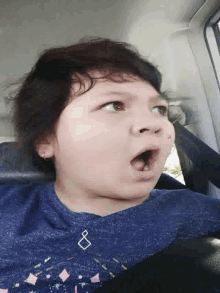a girl wearing a blue shirt with a diamond on it is making a funny face