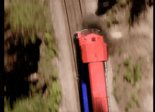 an aerial view of a red and blue train traveling down train tracks .