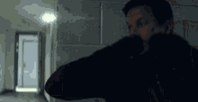 a man in a black jacket is standing in a hallway .