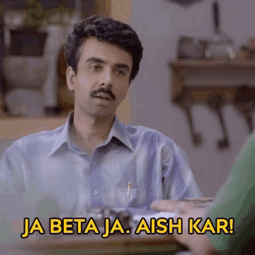 a man with a mustache is sitting at a table with the words ja beta ja aish kar