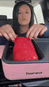 a woman is putting a piece of red cake into a pink topwit container