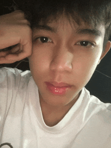 a close up of a young man 's face with his hand on his forehead