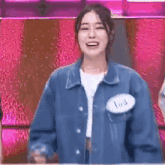 a woman in a blue jacket is smiling and giving a thumbs up sign .