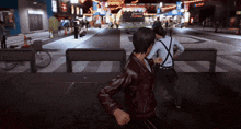 a man in a leather jacket is fighting another man on a street