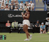 a woman holding a tennis racquet in front of a lexus banner