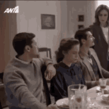 a group of people are sitting at a table with plates and a pitcher of beer .