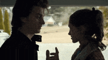 a man and a woman are looking into each other 's eyes while standing next to each other in a car .