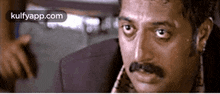 a close up of a man 's face with a mustache and a purple jacket .