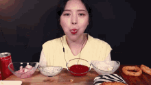 a woman is eating a hamburger with onion rings and a can of coke