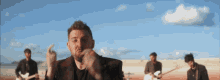 a man with a beard is giving the middle finger in front of a band