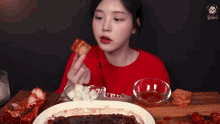 a woman in a red shirt is eating pizza