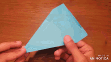 a person is holding a blue paper airplane in their hands