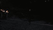a man in a black hooded sweatshirt stands in front of a blurry background of lights