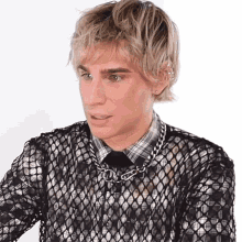 a man with blonde hair is wearing a black mesh shirt