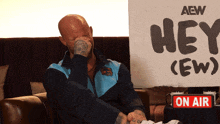 a man is sitting in front of a sign that says hey ( ew )