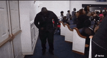 a man in a black suit is dancing in a church while a woman in a wheelchair sits in the aisle .