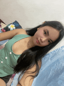 a woman in a green top is laying on a bed with a blue blanket