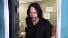 a man with long hair and a beard is standing in an open doorway .