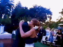 a bride and groom are kissing in front of a crowd with abc written on the bottom