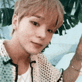 a close up of a young man wearing a white shirt and a bracelet