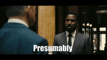a man in a suit and tie is talking to another man and the words presumably are visible