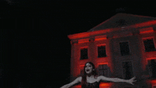 a woman stands in front of a building with red lights