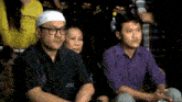a man wearing glasses sits next to a woman and a woman wearing a yellow shirt that says ' samurai '