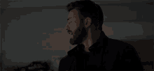 a man with a beard is making a funny face while standing in the dark .