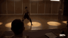 a woman in a black dress is dancing in a room with a bet logo in the corner