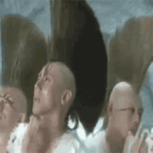a group of bald men with mohawks are standing next to each other in a room .