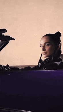 a woman is sitting in a purple car with headphones on her head