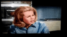 a woman in a blue shirt is making a face