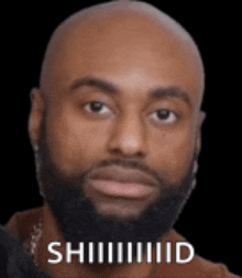 a bald man with a beard is looking at the camera with the words shhhhd written on the bottom of his face .