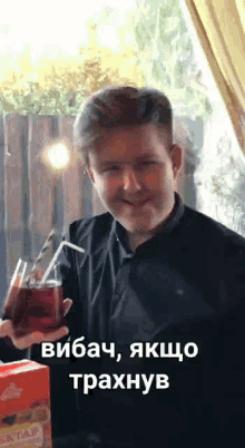 a man is holding a drink with a straw in his hand and smiling .